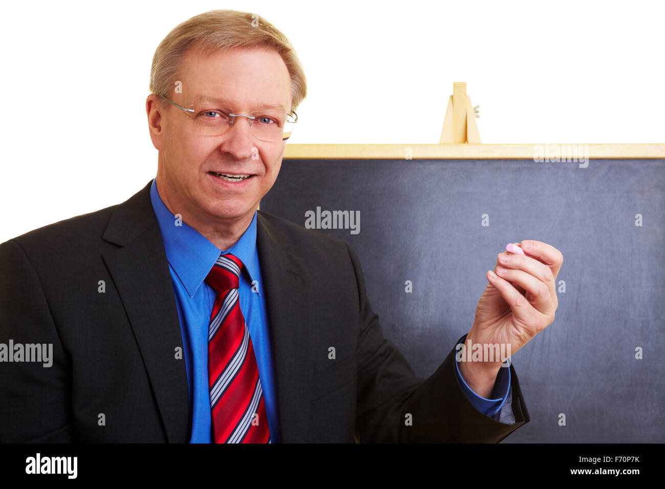 Enseignant heureux debout devant un tableau noir Banque D'Images
