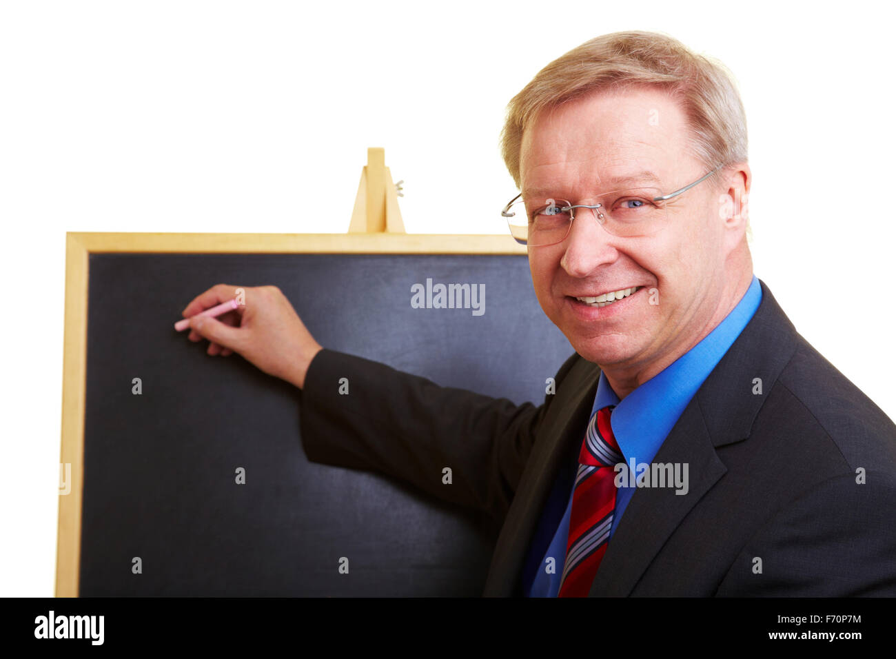 Enseignant heureux debout devant un tableau noir Banque D'Images