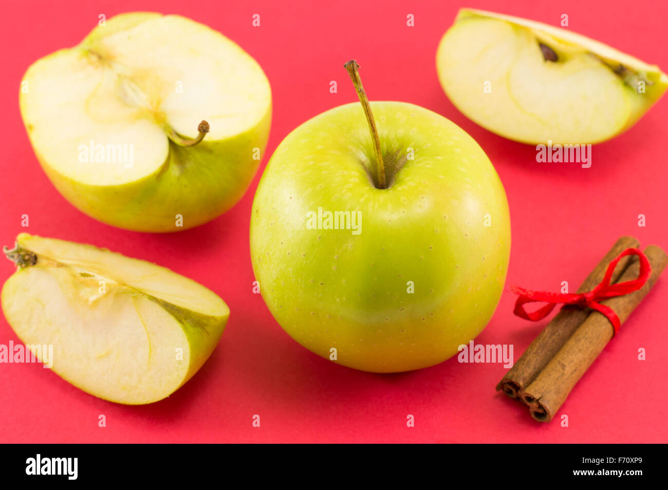 Des pommes fraîches et des bâtons de cannelle avec un ruban sur fond rouge Banque D'Images