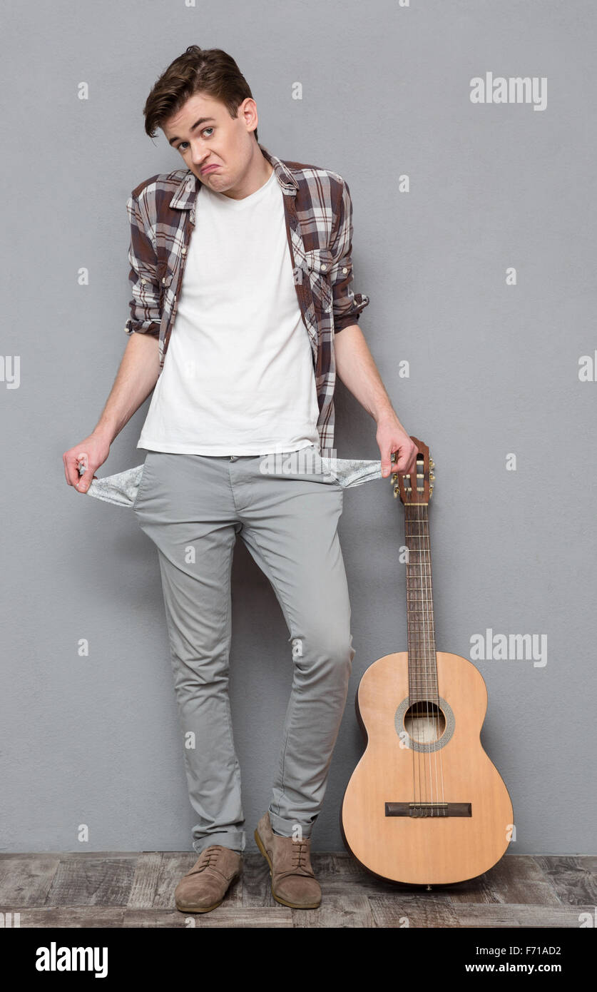 Portrait d'un jeune homme présentant ses poches vides sur gris bakground Banque D'Images