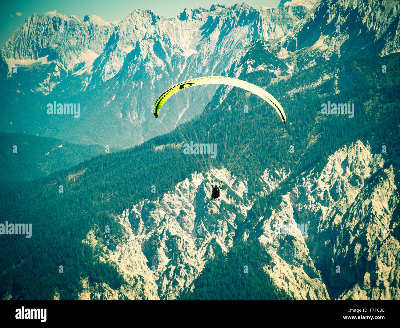 Vol en parapente sur la haute et solide gamme de montagnes des Alpes. Traitement croisé tonifié et filtrée stylisé Instagram stock photo Banque D'Images