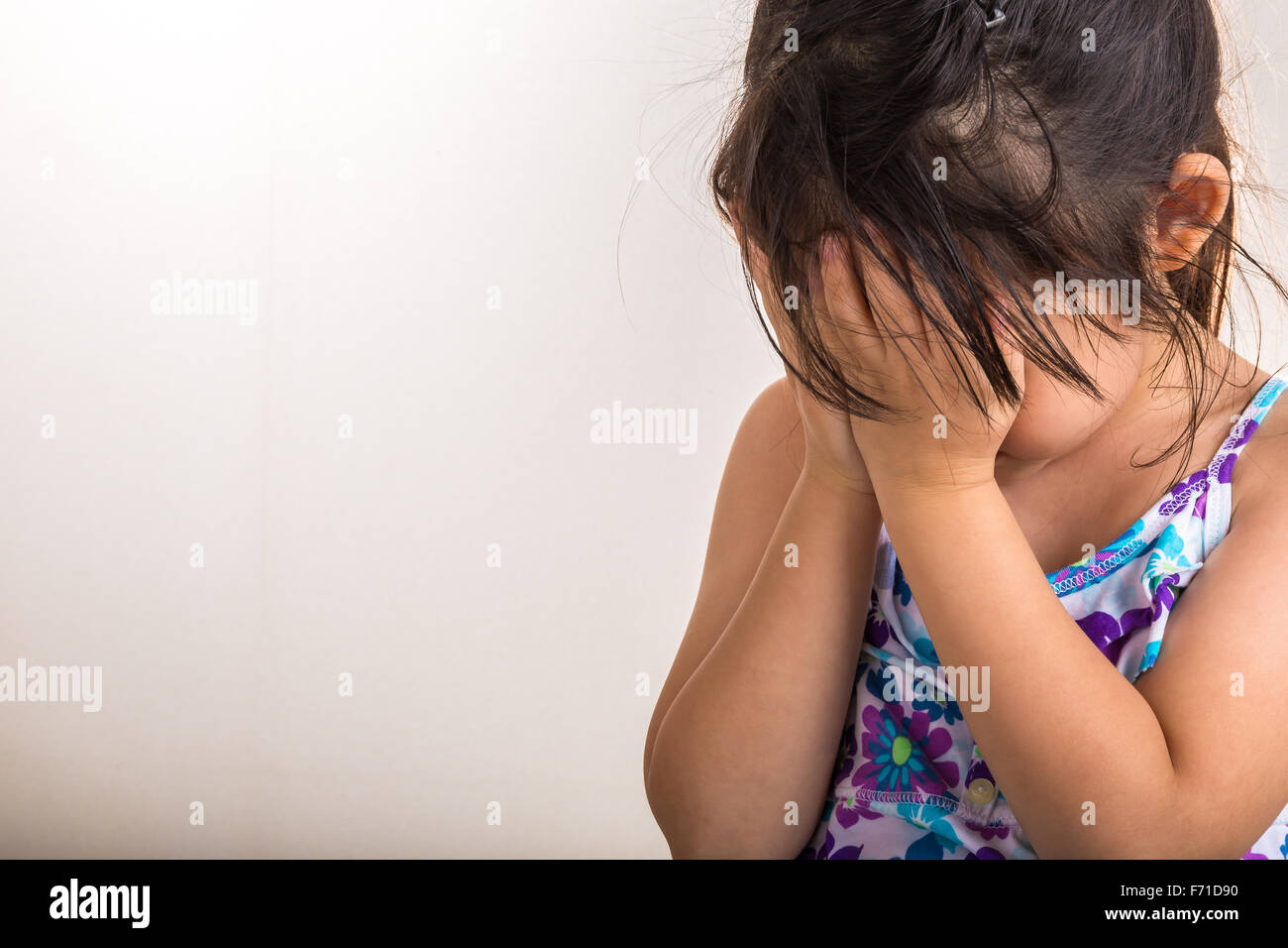 Petite fille joue hind-cache en couvrant son visage avec les mains. Banque D'Images