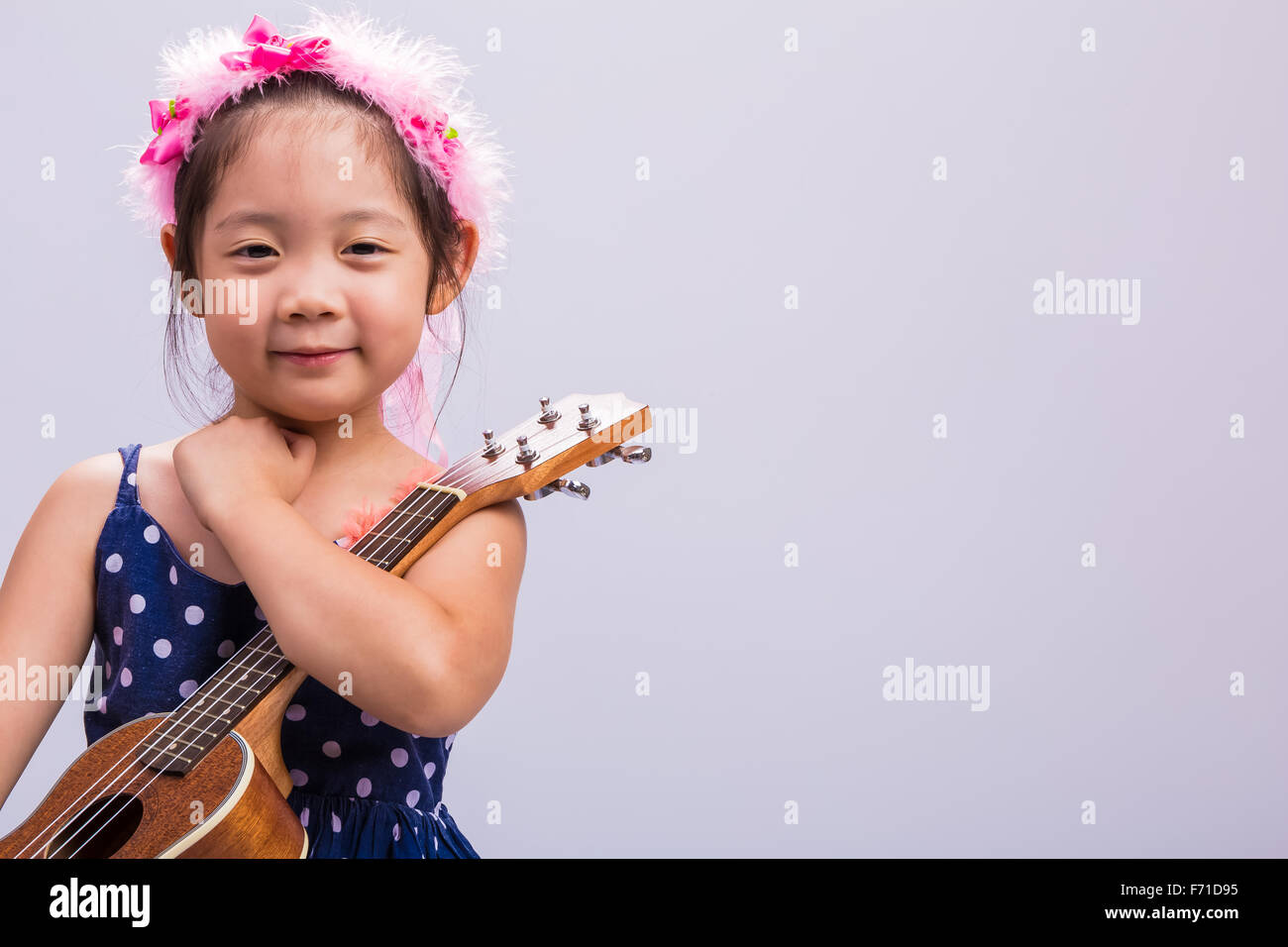 Petite fille avec son ukulélé, instrument de musique à cordes. Banque D'Images