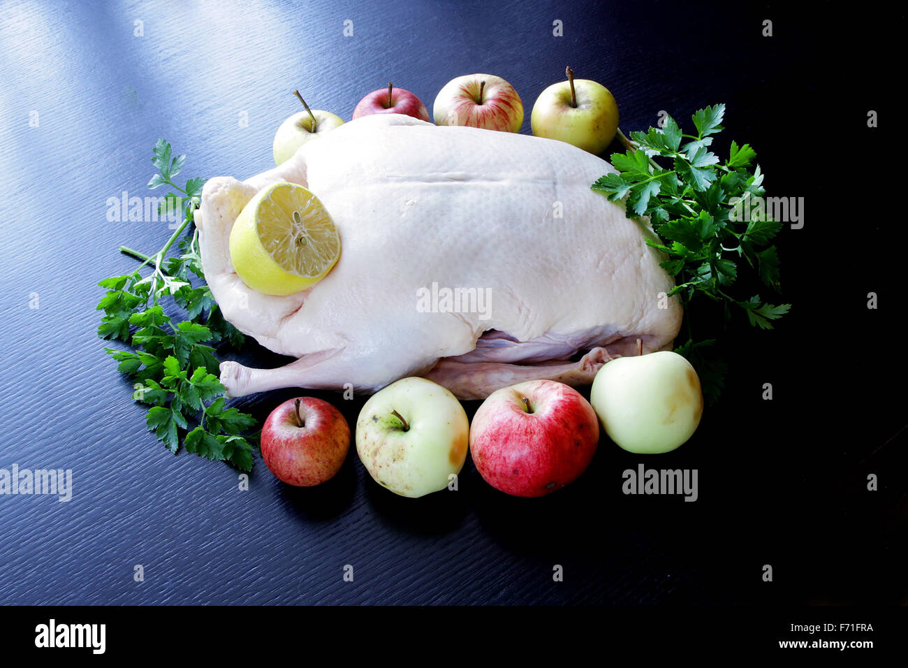 De canard cru drake prêt à cuire avec les légumes et les pommes sur noir Banque D'Images