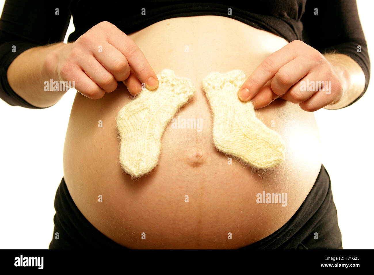 Les bras sur le ventre du ventre de maman enceinte holding tiny little laines bébé d'amour fond blanc Banque D'Images