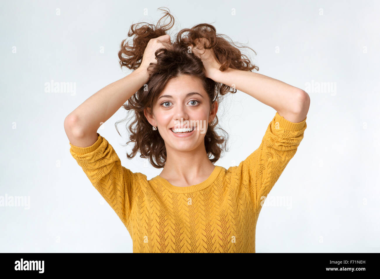 Portrait of a smiling woman holding her décontracté cheveux isolé sur fond blanc Banque D'Images