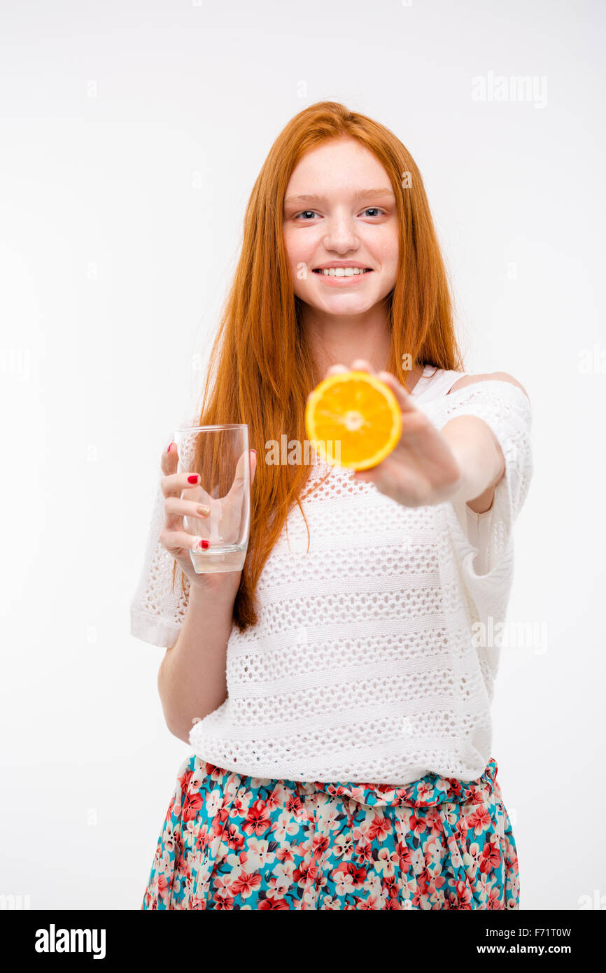 Franc joyeux happy pretty redhead girl in white top et jupe florale holding verre vide et l'offre orange mûre Banque D'Images