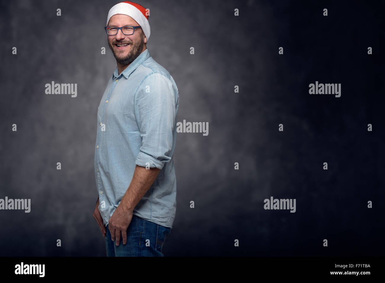 Trois quart d'un homme d'âge moyen, le port de Santa Clause Hat, souriant à la caméra, avec passage des bras sur sa poitrine, Aga Banque D'Images