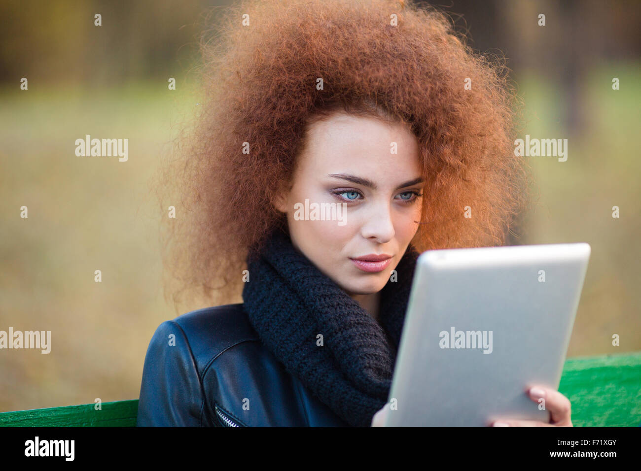 Portrait d'une belle femme avec des cheveux bouclés using tablet computer outdoors Banque D'Images