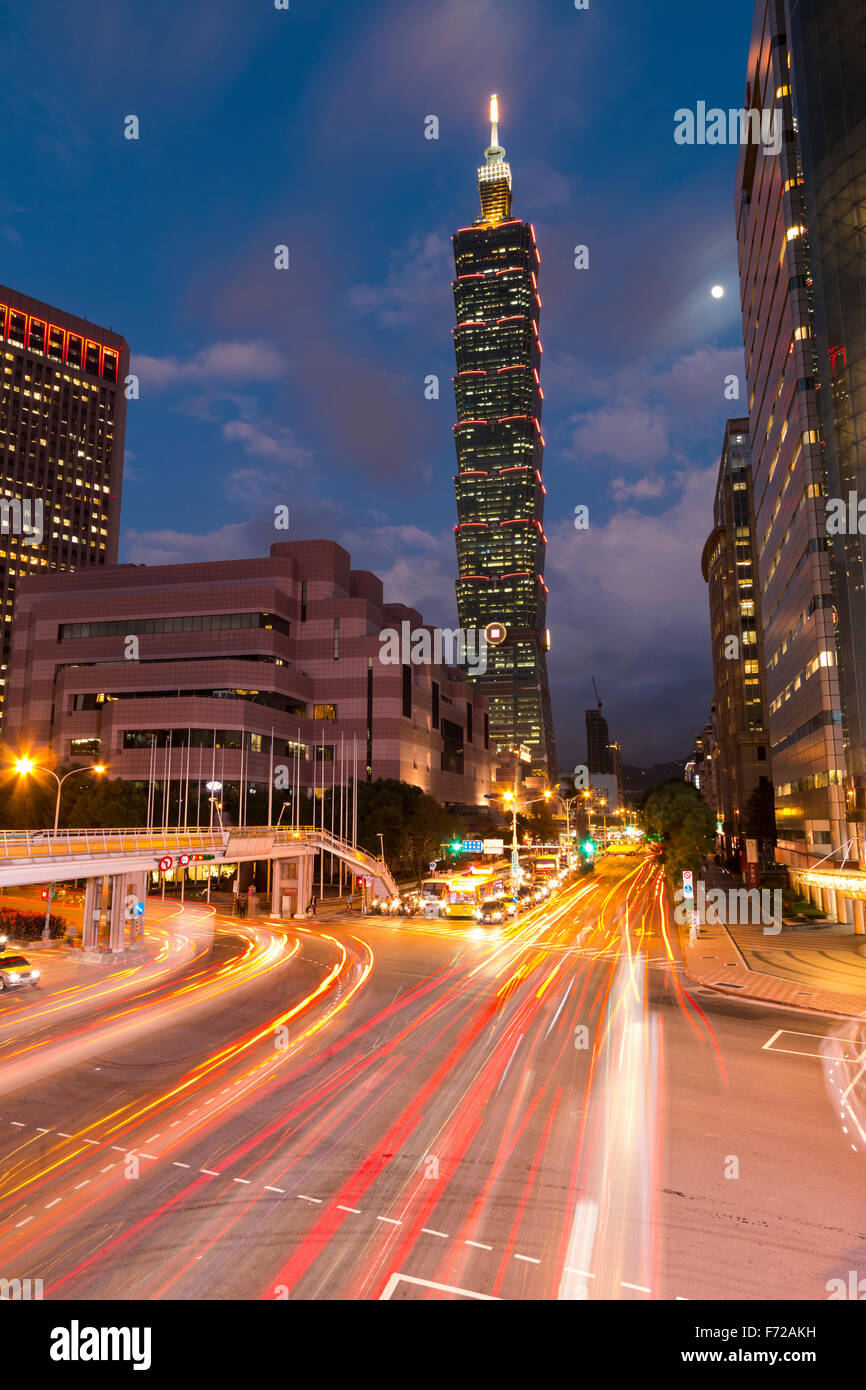 La lune brille au-dessus de Taipei 101, à 518 m de l'un des édifices les plus hauts du monde, et le Taipei World Trade Center que le trafic passe par une intersection achalandée dans le quartier des affaires de la ville de Xinyi au crépuscule. Banque D'Images