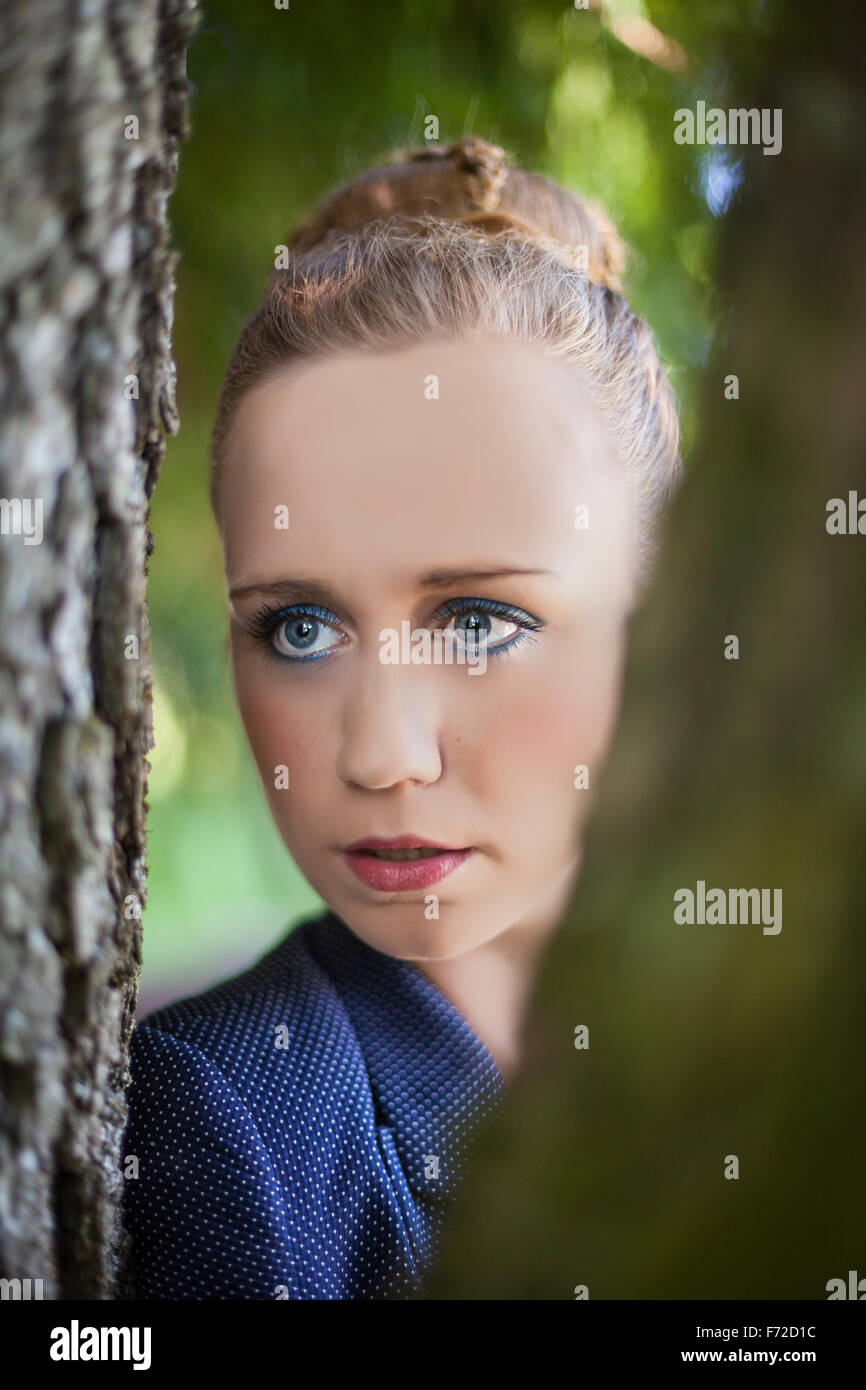 Jeune femme à travers les troncs d'arbres Banque D'Images