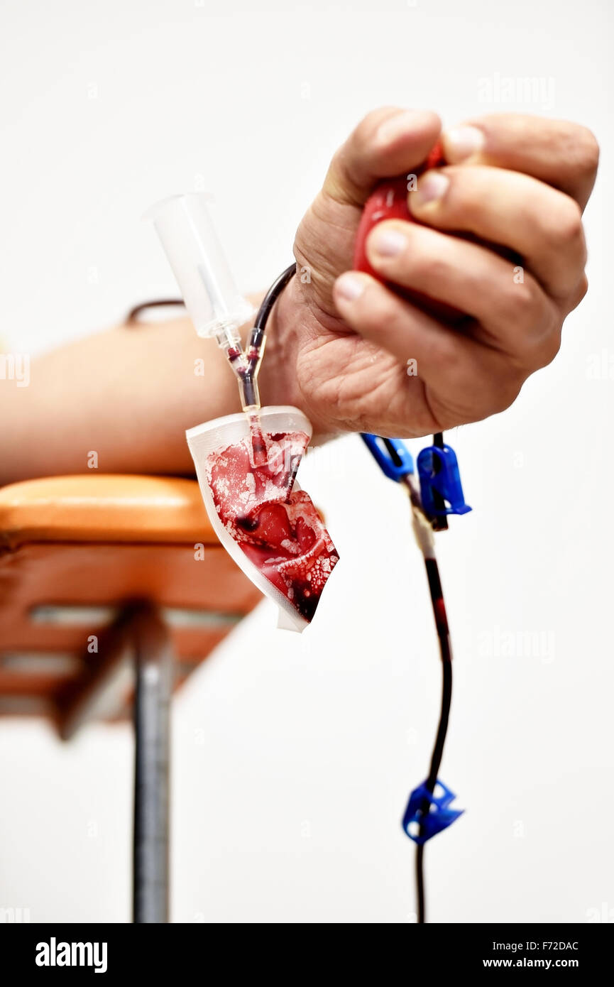 Détail de la main d'un don de sang, serrant une balle médicale et une poche de sang en plastique dans un hôpital Banque D'Images