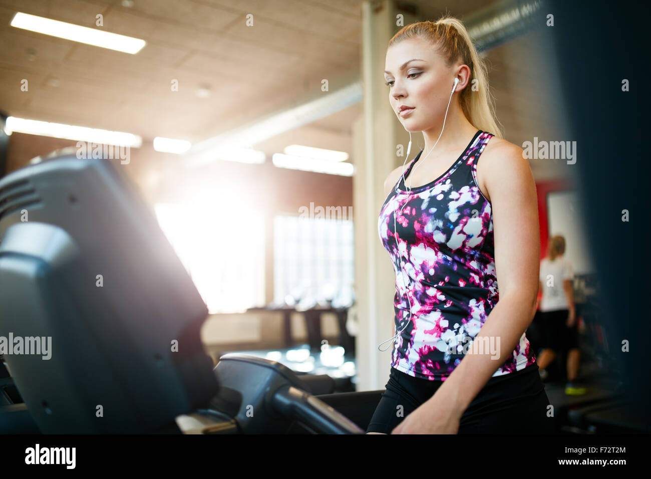 Tourné d'une femme marche sur le tapis roulant à la salle de sport. Les jeunes femmes ciblées de l'exercice à un club de santé, une formation sur l'équipement d'exercice. Banque D'Images