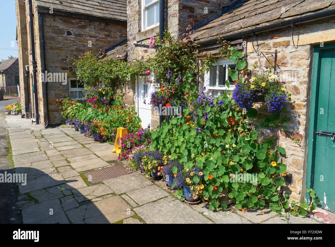 Paniers de fleurs suspendus à une maison traditionnelle en pierre dans le village de Blanchland County Durham, campagne anglaise. Banque D'Images