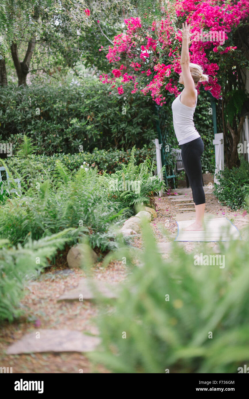 Blonde woman doing yoga dans un jardin. Banque D'Images