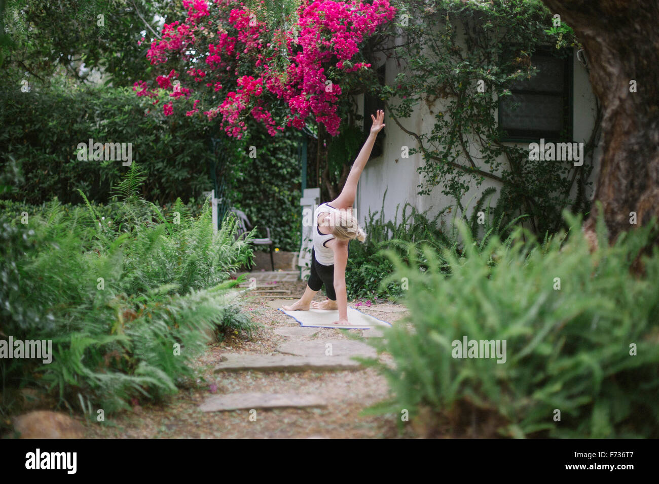 Blonde woman doing yoga dans un jardin. Banque D'Images