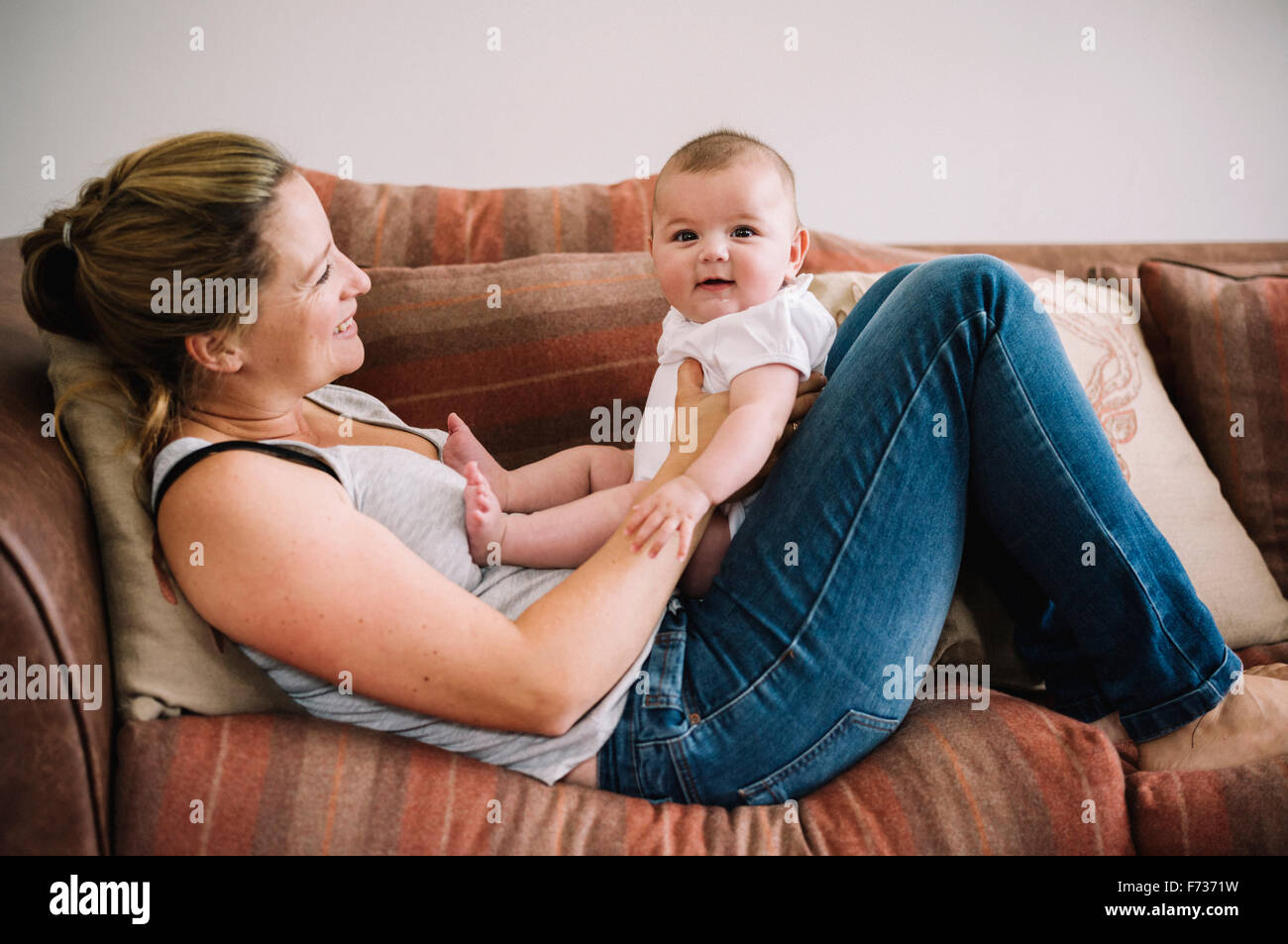 Une femme allongée sur un canapé à jouer avec une petite fille. Banque D'Images