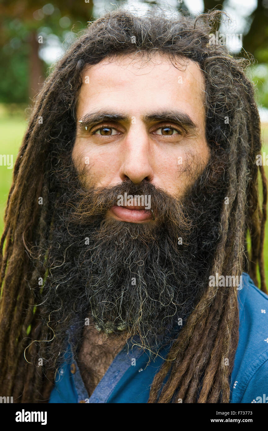 Un homme aux longues dreadlocks dans une chemise bleue. Banque D'Images
