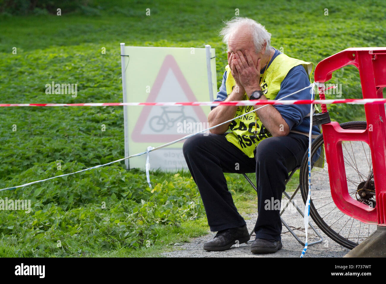 Cyclocross Marshal est assis sur un tabouret pliant avec son visage dans les mains Banque D'Images