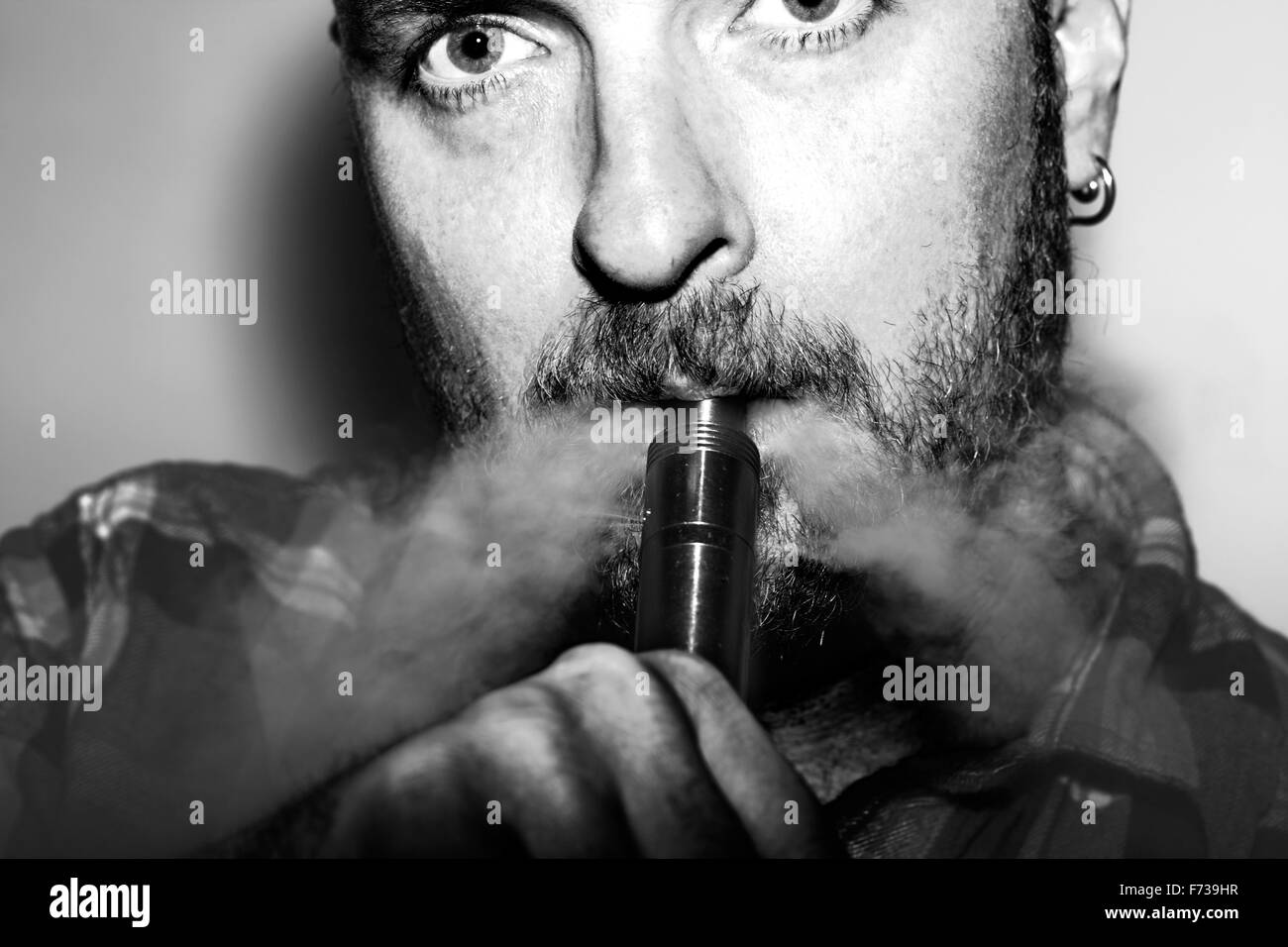 L'homme exhale de vapeurs d'une grande aciérie e-cigarette. Banque D'Images