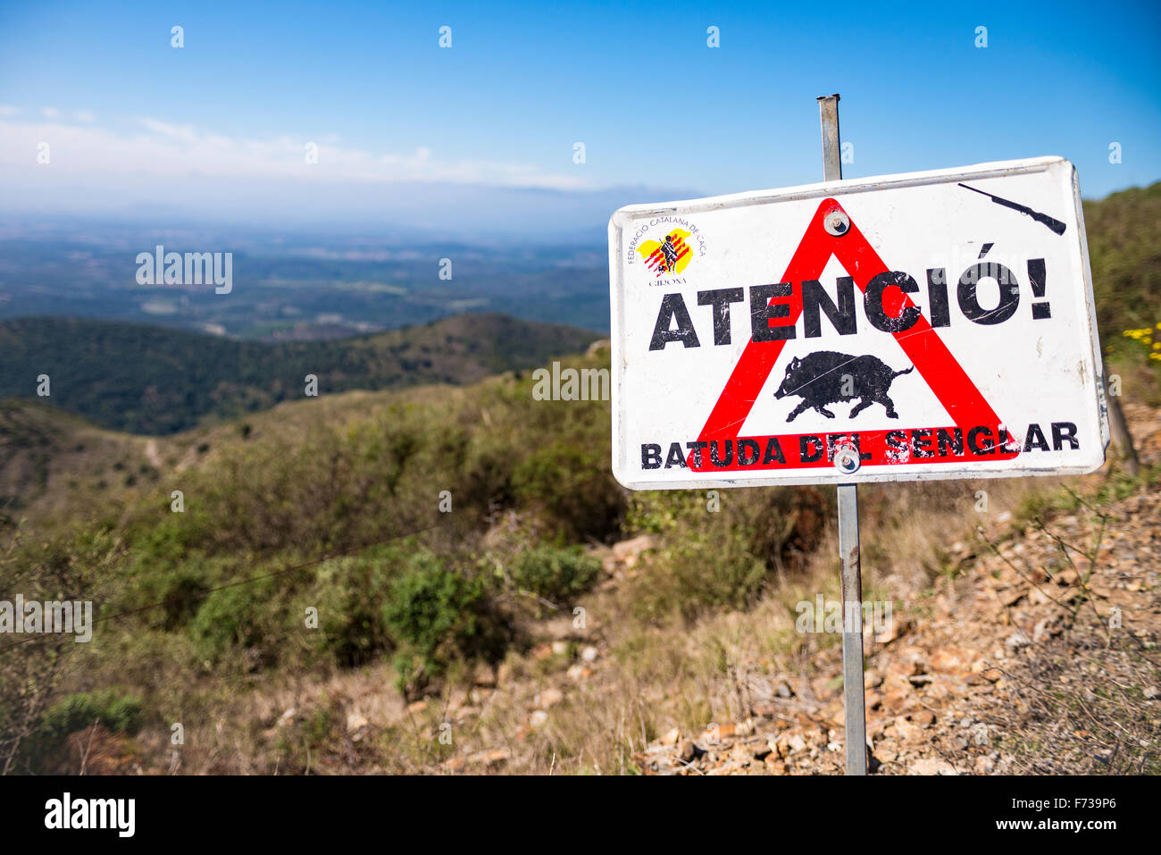 Une image de pays de collines côté avec un signe en premier plan qui lit, "attention ! Chasse au sanglier' en Catalan. Banque D'Images