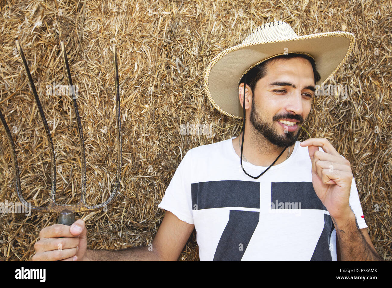 Beau cowboy tenant une fourche en stable Banque D'Images