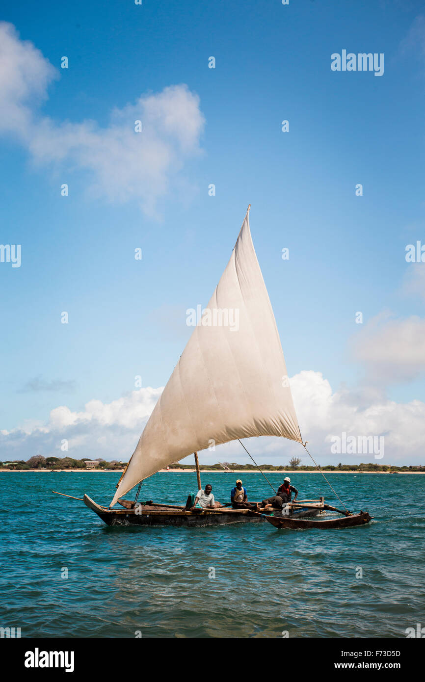 LAMU, Kenya, Afrique. Trois hommes d'une petite voile voilier boutre dans turwuoise avec eaux plage à distance. Banque D'Images