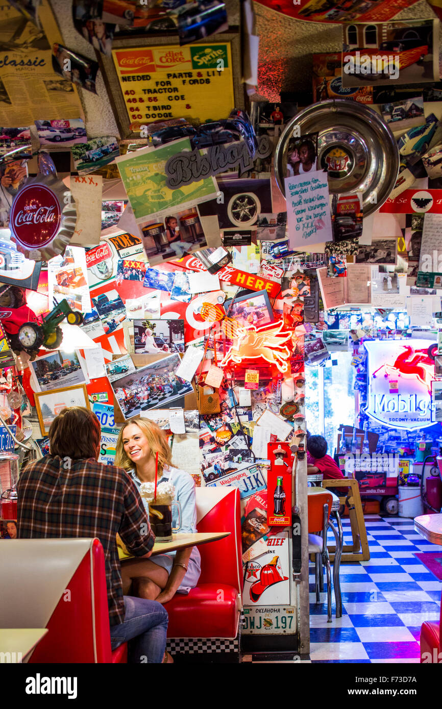 Un couple manger dans un fast food restaurant avec un thème des années 50 où les murs sont pleins de vintage items de collection. Banque D'Images