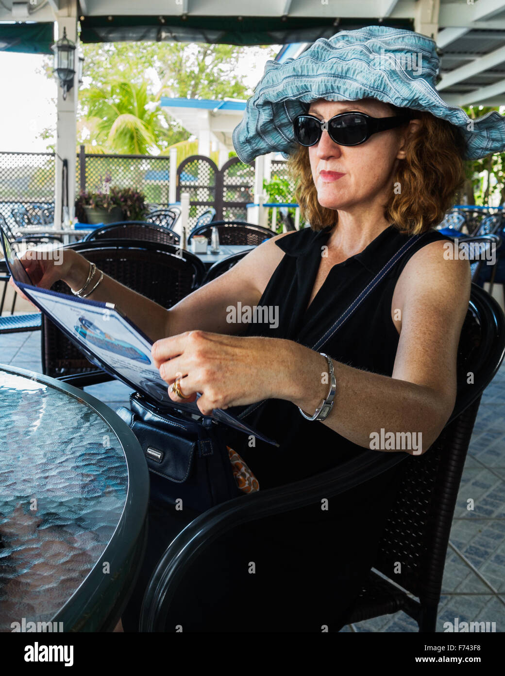 A 50 ans caucasien femme études sérieusement un menu à un café sur la plage de Sainte Croix, Îles Vierges des États-Unis. Banque D'Images