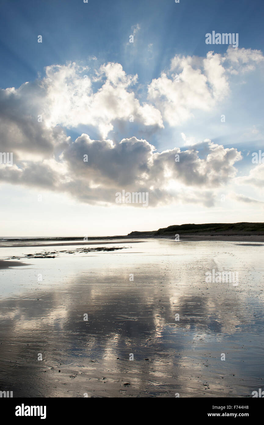 Les rayons du soleil et nuages reflétée à marée basse sur une plage. Scremerston, Weymouth, Dorset, Angleterre. Banque D'Images