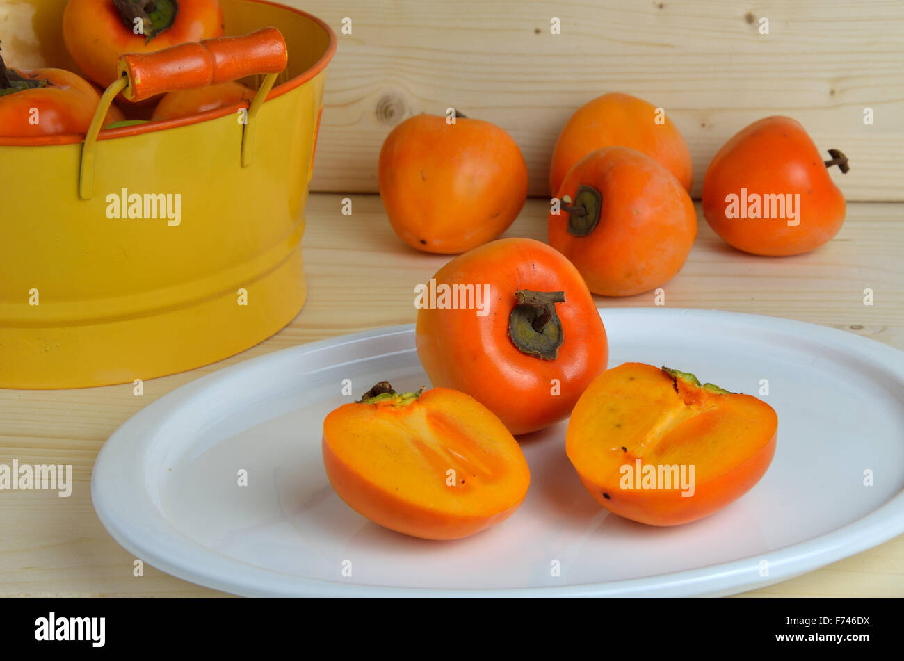 Kaki pomme sur l'assiette blanche et orange tin coupe de fruits en arrière-plan Banque D'Images