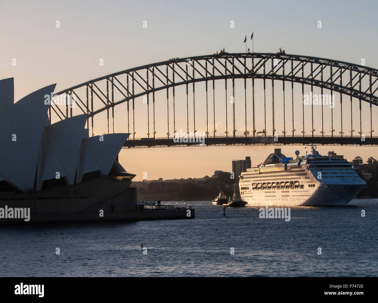 Bateau de croisière de quitter le port de Sydney au coucher du soleil et passe entre l'Opéra et le Harbour Bridge , Australie Banque D'Images