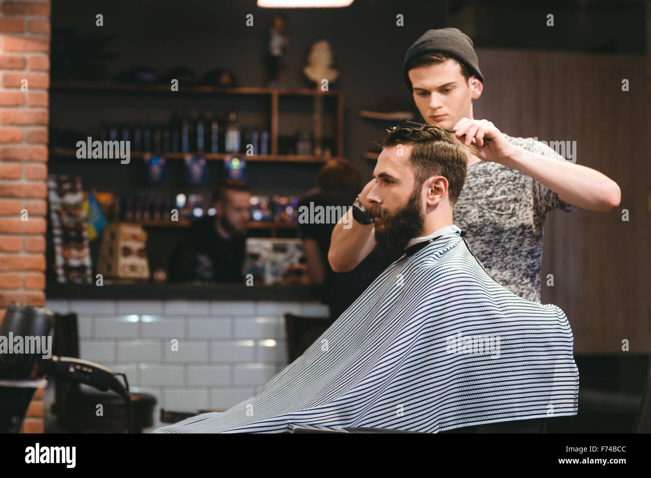 Jeune beau salon de coiffure de décisions de coupe homme barbu attrayant dans ce type de Banque D'Images