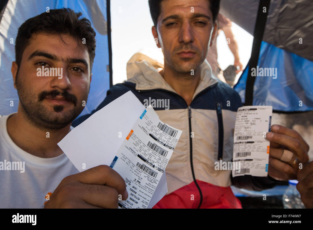 Des migrants syriens fuyant la guerre et la fuite vers l'Europe, qui ont débarqué sur l'île grecque de Lesbos, sur la côte nord à Efthalou, ici holding up billets qui leur permettra à l'extérieur de l'île à la Grèce continentale. Jusqu'à 4 000 migrants par jour sont l'atterrissage sur l'île et écrasante les autorités. Ils sont traficked illégale par les trafiquants qui peuple turc frais jusqu'à 2 000 $ par personne pour un trajet d'une demi-heure dans un logement surpeuplé inflateable bateau de la Turquie continentale à Lesvos. Banque D'Images