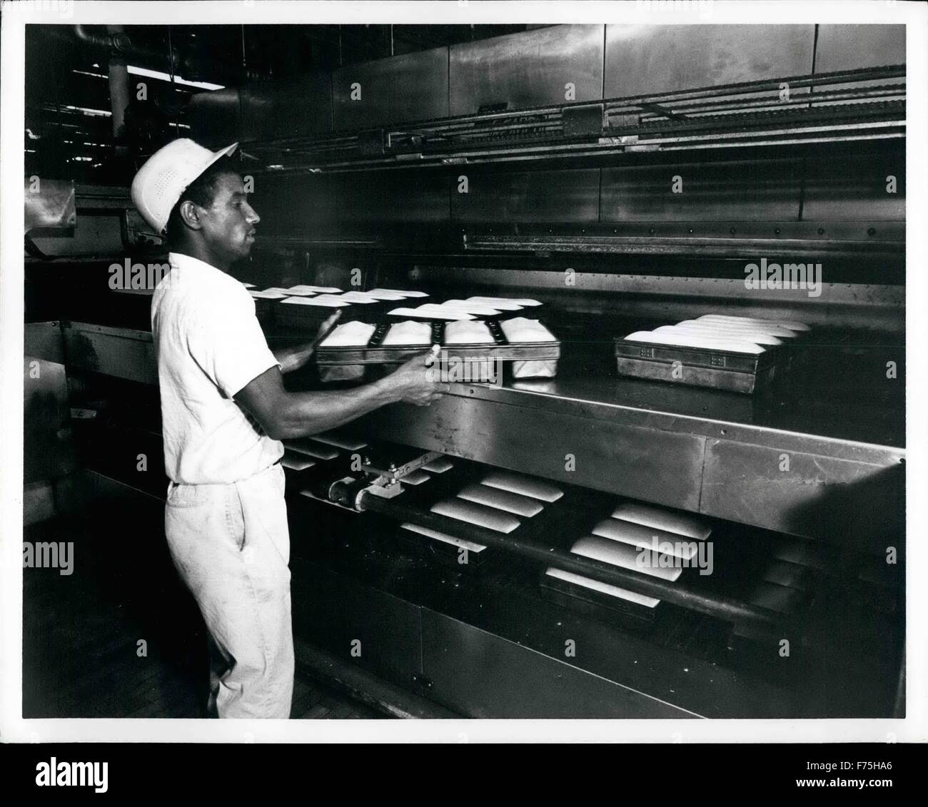 1972 - Après le bouillon et tous les autres ingrédients ont été mélangés dans la pâte bouilloire, la pâte est coupée en taille mesurée, est tombé dans l'plats de cuisson, puis envoyé à la preuve casiers où il est autorisé à prendre la parole dans des conditions soigneusement contrôlées de la chaleur et de l'humidité. En photographie, la pâte est mis sur déménagement courroie qui s'en chargera dans le four. Des amours de pain Sunbeam émergent du four sur leur chemin vers le processus de refroidissement. © Keystone Photos USA/ZUMAPRESS.com/Alamy Live News Banque D'Images