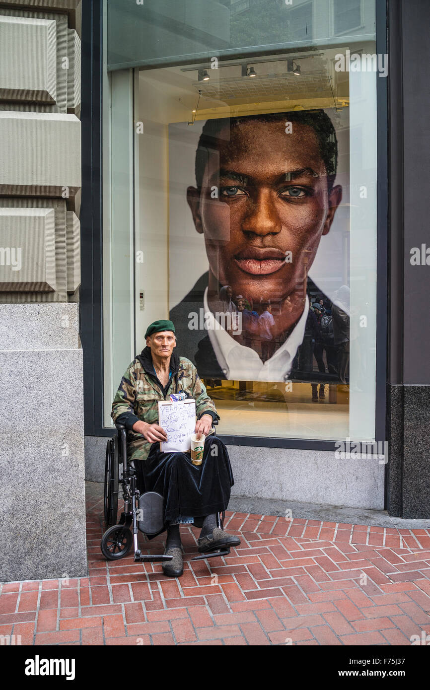 Un vers le bas-et-out vétéran militaire dans un fauteuil roulant & Green Beret est titulaire d'un Starbucks tasse la mendicité en face d'un magasin haut de fenêtre. Banque D'Images