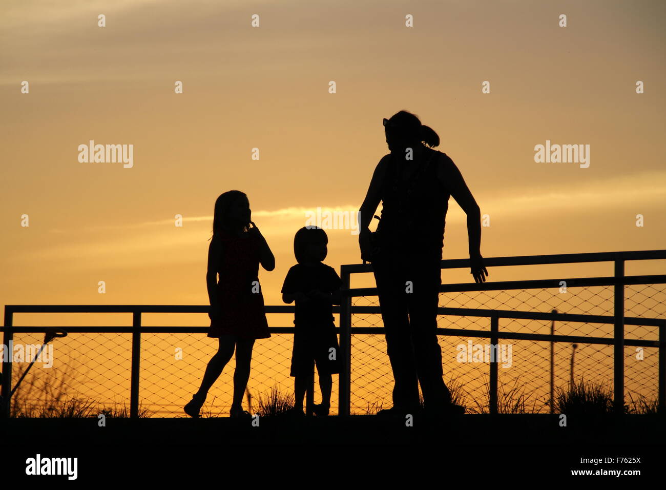 Silhouette de mère avec les enfants avec le coucher du soleil dans l'arrière-plan Banque D'Images