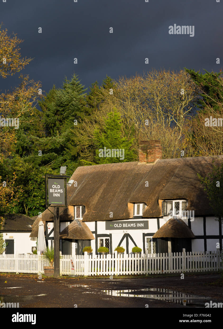 Les vieilles poutres Inn à Ibsley près de Fordingbridge, Hampshire, en plein soleil sous un ciel sombre. Banque D'Images