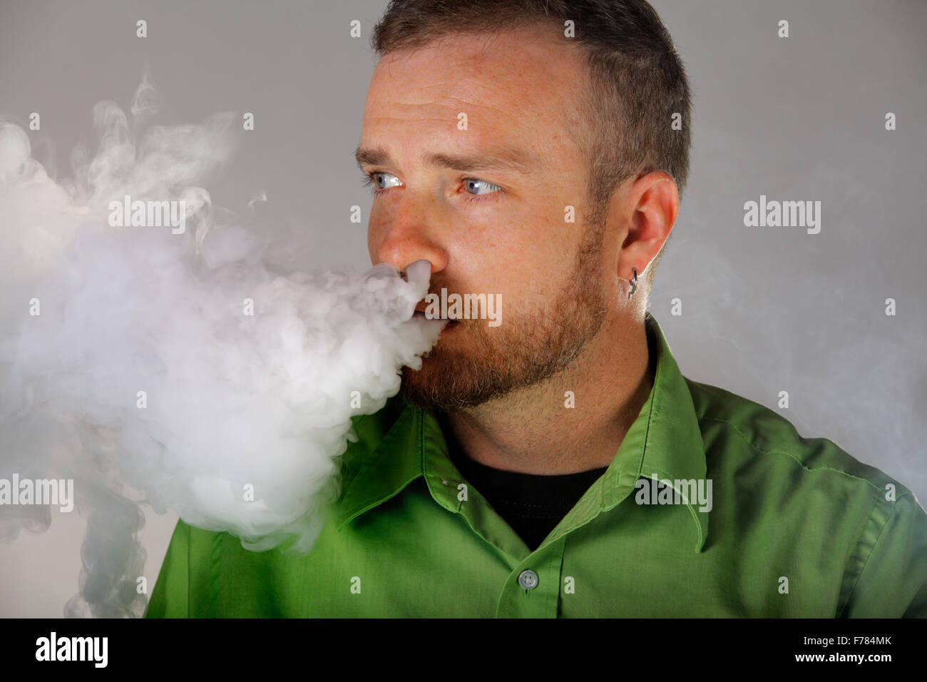 Un homme souffle de vapeur d'e-cigarette de son nez et la bouche. Banque D'Images