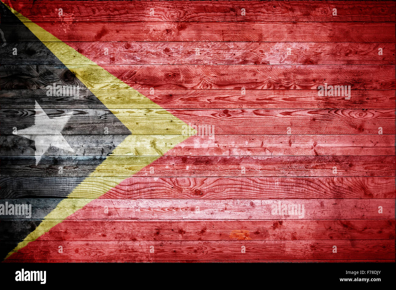 Une vignetted image de fond du drapeau du Timor Leste sur les planches de bois d'un mur ou le plancher. Banque D'Images