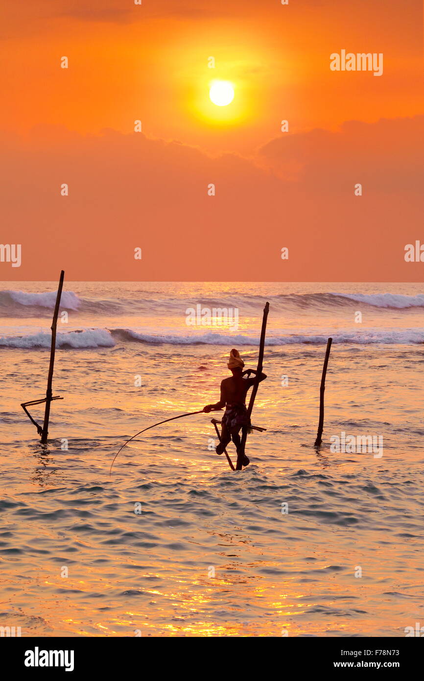 Pêcheurs sur pilotis au coucher du soleil tropical, Koggala Beach, au Sri Lanka, en Asie Banque D'Images