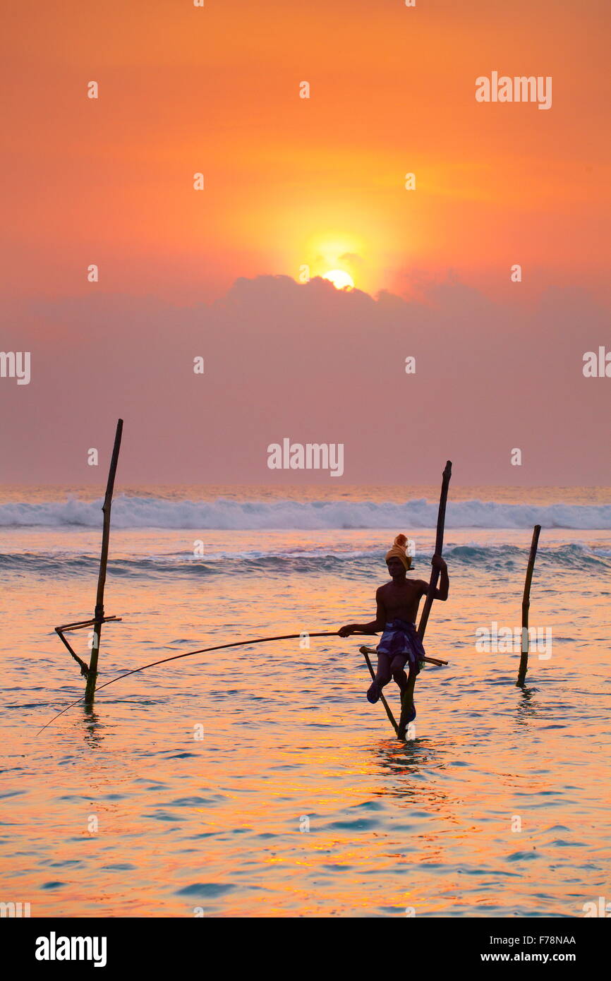 Sri Lanka - pêche pêcheur sur pilotis dans la mer, coucher du soleil tropical à Koggala Beach, en Asie Banque D'Images