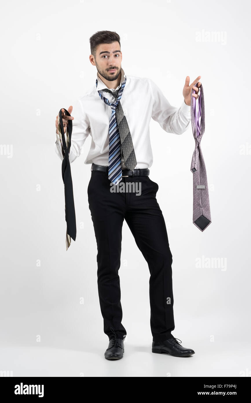 Jeune homme confus essayant de choisir cravate droite. La longueur du corps  plein sur fond gris portrait studio Photo Stock - Alamy