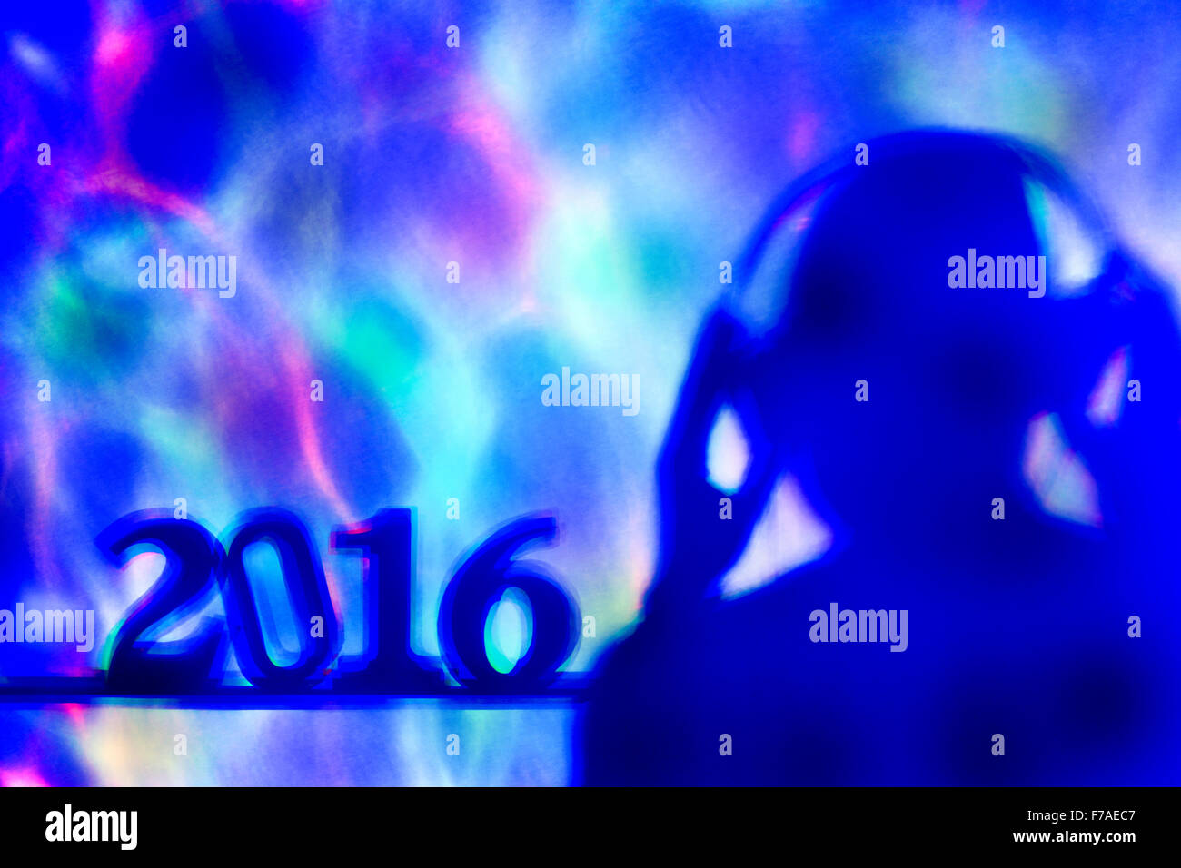Lumières colorées projetées sur le nombre 2016, comme la nouvelle année, et d'un disc jockey homme portant des écouteurs dans un club de danse Banque D'Images