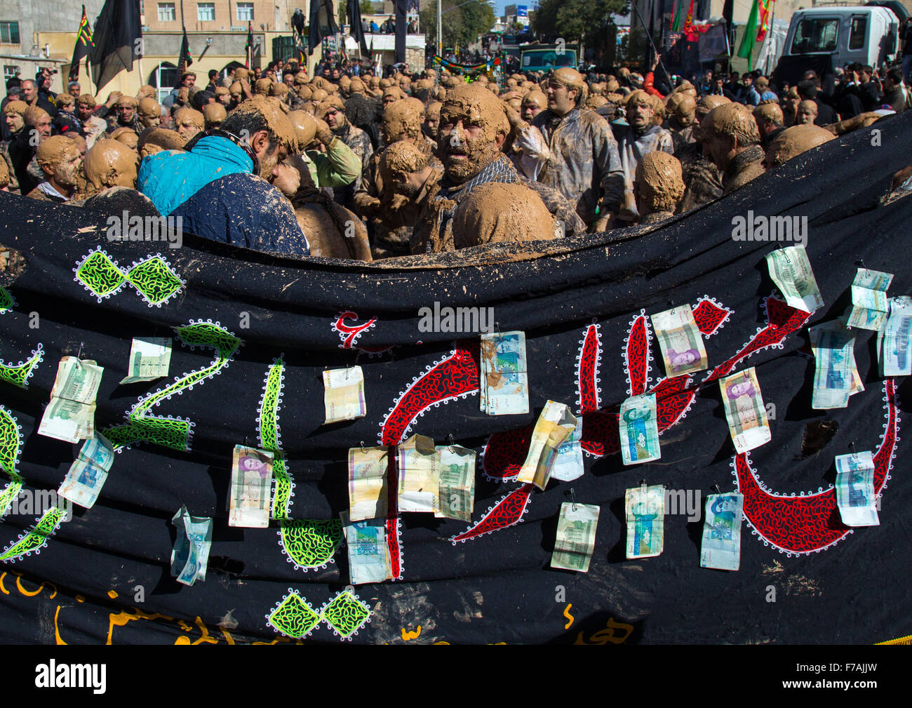 Les hommes musulmans chiites iraniens couvert de boue devant un drapeau avec des billets de banque lors de la province du Kurdistan, Ashura, Bijar, Iran Banque D'Images