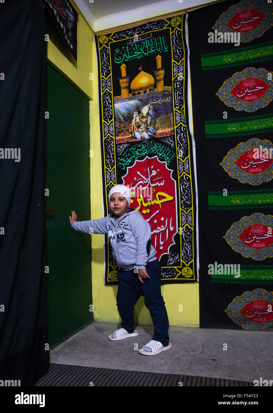 Enfant chiite iranien Fermer la porte où sont les gens qui attendent pour recueillir la nourriture durant la charité Nazri Muharram, Province de Golestan, Gorgan, Iran Banque D'Images