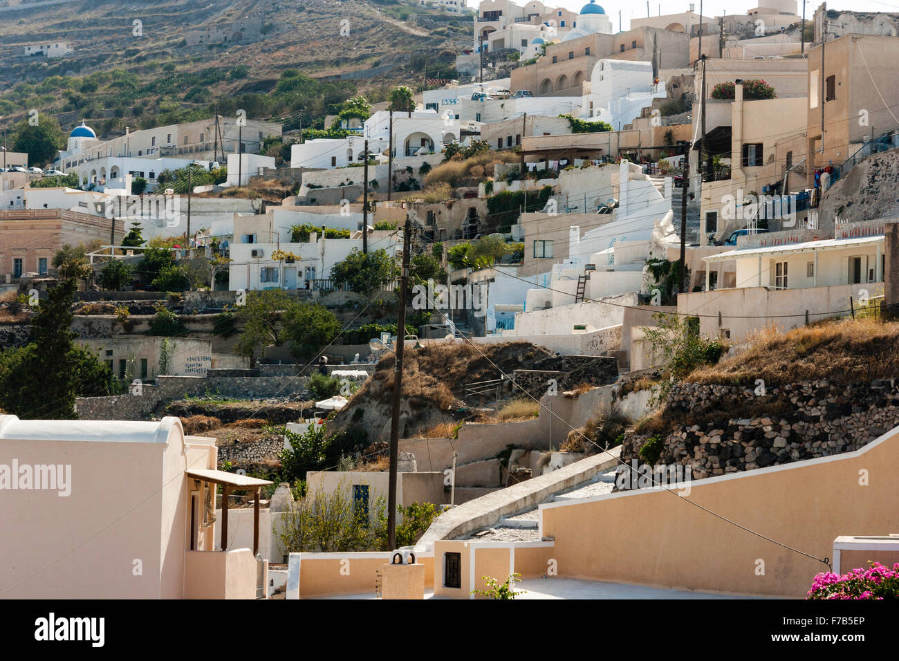 Santorini, Exo Gonia. Vue générale de la partie de petites Cyclades village, ville construite sur des terrasses à flanc de montagne. Deux églises au dôme bleu, différentes maisons. Banque D'Images