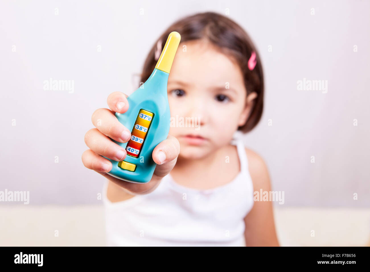 Cute little girl montrant un jouet thermomètre. Plus isolé sur fond blanc Banque D'Images