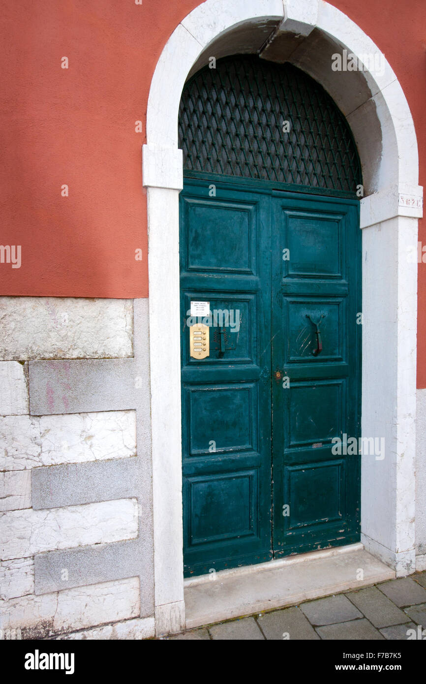Une porte verte sur un mur avec des briques gris rose Banque D'Images