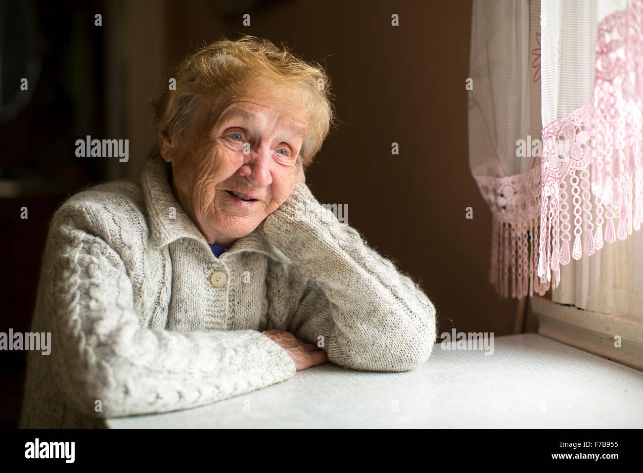 Femme âgée est assis à une table près de la fenêtre. Banque D'Images